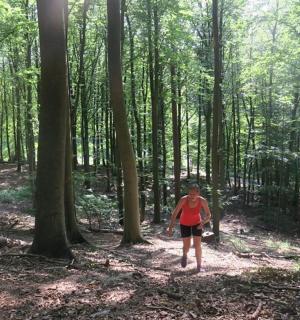 a woman walking through a wooded area