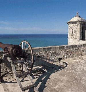 a cannon on a wall next to the ocean