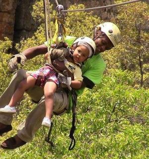 muž držící malou holčičku na zip line