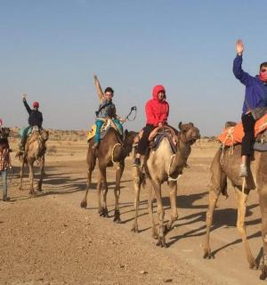skupina lidí jedoucích na koních v poušti