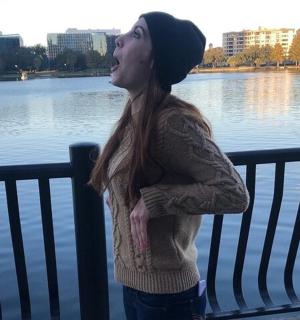 一名女子站在水边的长椅旁