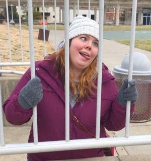 a woman is standing behind a gate