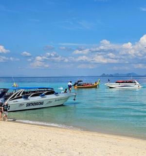 人们站在海滩上，水中有船
