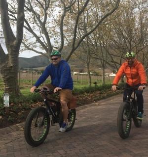 two men are riding bikes down a road