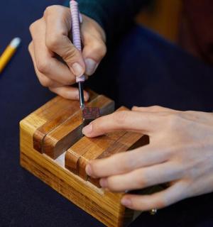 a person cutting a piece of wood with a knife