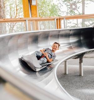 一名年轻人坐在操场上的滑梯上