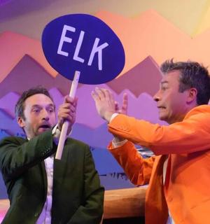 舞台上有两个男人举着写着“精灵”的牌子