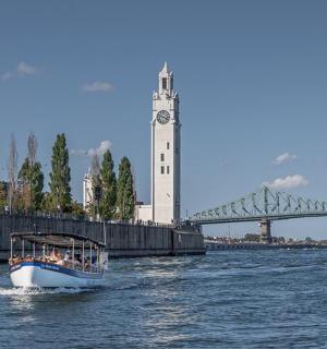 a boat in the water with a clock tower and a bridge