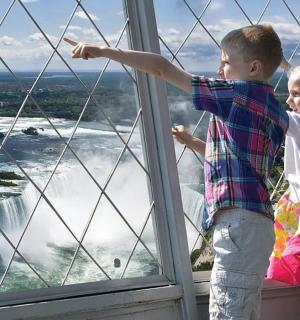 两个孩子从窗户望向瀑布