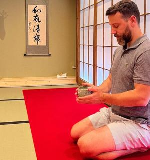 a man sitting on a red carpet holding a cup