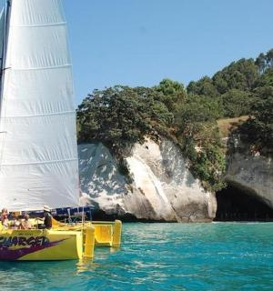 洞穴旁水中的一艘黄色帆船