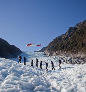 a group of people standing on a glacier with a plane