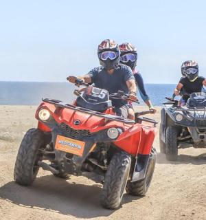 两个人在海滩上骑着四轮摩托车