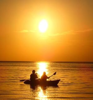 two people in a boat in the ocean at sunset