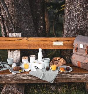 piknikový stůl s jídlem a batoh na lavičce
