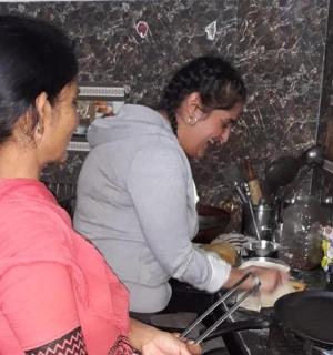 two women standing in a kitchen preparing food