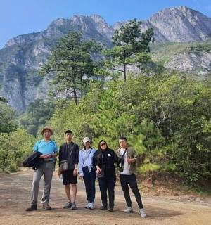 a group of people standing on a dirt road with mountains in the background