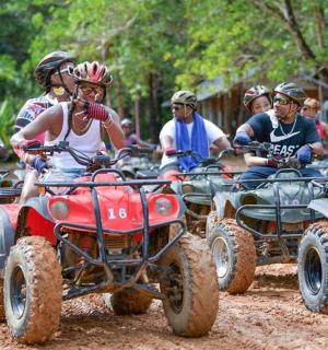 一群人骑着四轮摩托车在土路上行驶