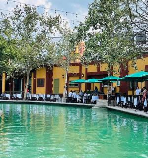 a pool of water with tables and chairs next to a building