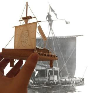 一只手拿着一艘船的木制模型
