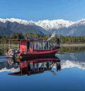 a red boat sitting on the water with mountains