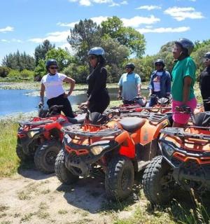 一群人站在河边小路上的四轮摩托车旁