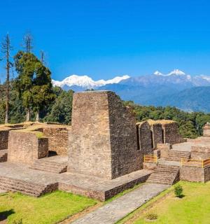 an old building on a hill with mountains in the background
