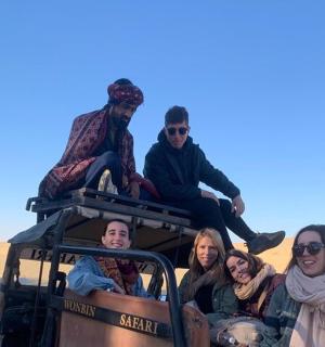 一群人坐在沙漠中的一辆卡车后面