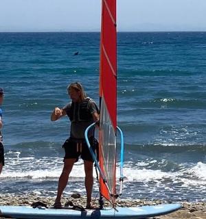 eine Gruppe von Menschen steht mit einem Segel am Strand