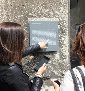 两名女子用手机看着一块标志牌