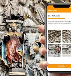 en person, der holder en mobiltelefon foran en statue
