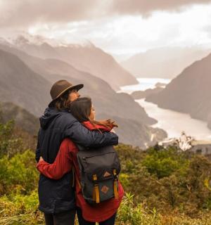 a man and woman standing on a hill looking at a valley