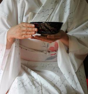 a person in a white robe holding a cup