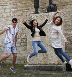 skupina tří lidí skákajících před sochou