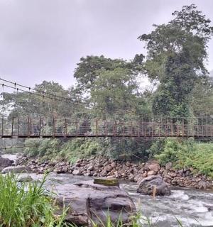 a person crossing a suspension bridge over a river