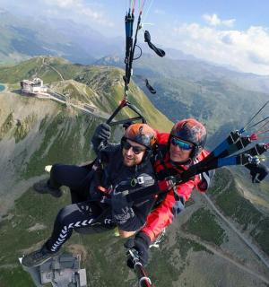two people are flying in the air with a parachute