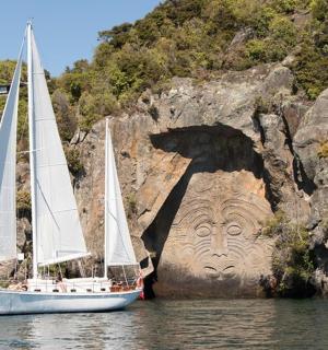 two boats in the water next to a stone face