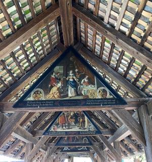 a ceiling of a wooden building with a painting on it