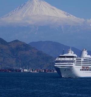 a cruise ship in the ocean with a mountain in the background