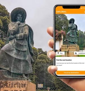 a person holding a cell phone in front of a statue