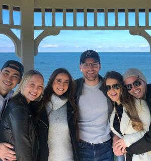 група људи позира за фотографију испред океана