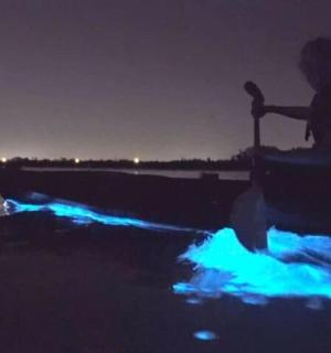 a man sitting in a boat on the water at night