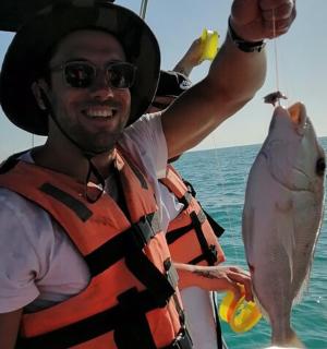 船上抱着鱼的男人