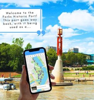 a person holding up a cell phone in front of a river