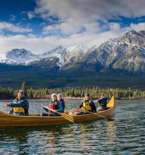 一群人乘独木舟在群山环绕的湖面上