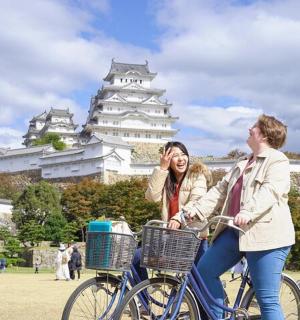 two women riding a bike in front of a castle