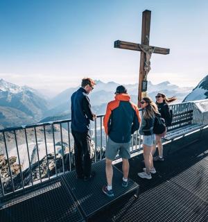 a group of people standing at the cross on top of a mountain