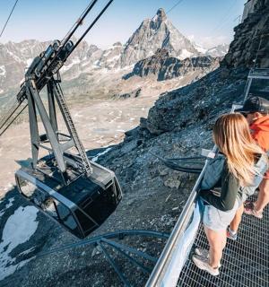 a group of people standing on a cable car over a mountain