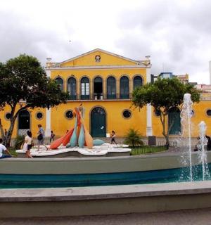 a yellow building with people sitting in front of a fountain