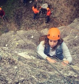 žena v oranžové helmě ležící na skalách